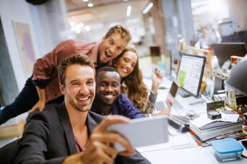 Young group of people taking a selfie while working in the office together