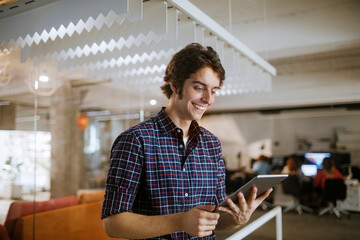 Obraz premium Young man using a digital tablet while working in a startup company office