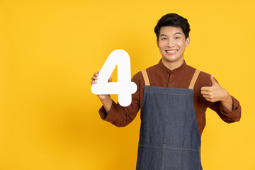 Restaurant owner sme young Asian man holding number 4 or four isolated on yellow background