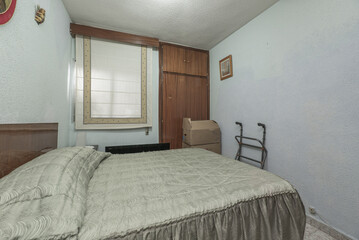A bedroom with a double bed with a green bedspread, dark wood cabinets