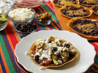Vegetarian Tostada on White Plate with Toppings in Background