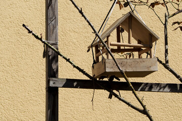 wooden open birdhouse on the background of the yellow wall of the house. Bird house with food. nature