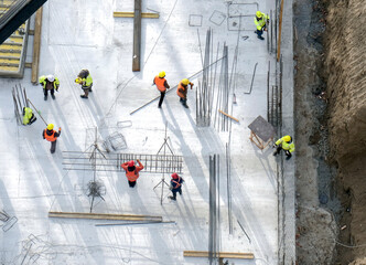 Top view: builders in orange and yellow uniform at the construction site