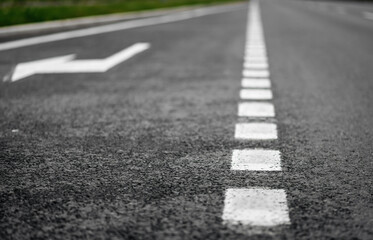 Obraz premium Road markings. Depth of field shot focused on asphalt close to the camera. Road with additional lane for turning right.