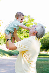 Grandfather with his baby grandson in his arms playing in the park