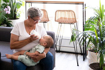 Close-up of a grandmother feeding a bottle to her baby grandson
