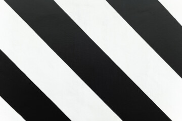 Concrete wall painted with black and white color in diagonal stripe lines, zebra pattern, decorated modern building, concrete texture