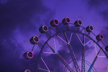 Ferris wheel ride at amusement park with purple night sunset sky background - obrazy, fototapety, plakaty