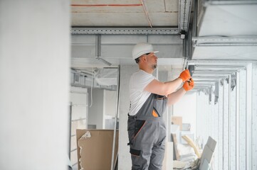hvac services - worker install ducted pipe system for ventilation and air conditioning in office.