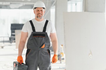Portrait of a builder in the process of working on a construction site indoors