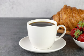 Breakfast with croissants, coffee and strawberries on gray background. French or italian breakfast.