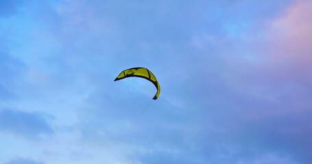 Boarding kite soars in air high in sky. Millennial outdoor lifestyle is boarding on waves with kite in wild nature. Cinematic video of Millennial kiteboarding outdoor lifestyle to feel freedom.