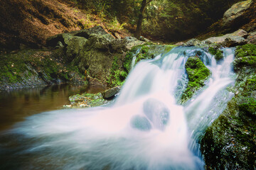 Waterfall between rocky stream in the mountains