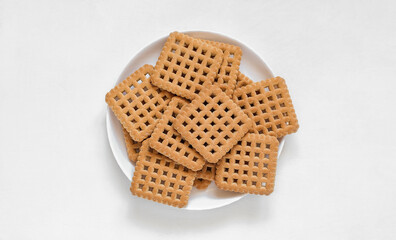 White plate with sweet square biscuits on a white background.