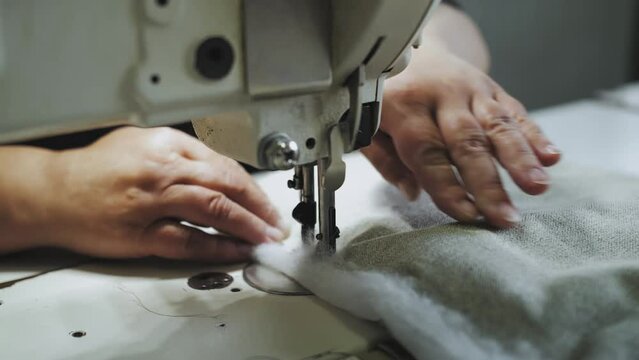 Woman's hands sewing fabric on the automatic sewing machine. Close-up seamstress sews elements for furniture.