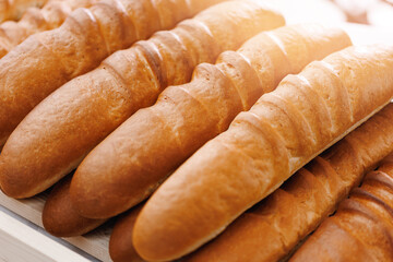 Closeup fresh bread with golden crust on store shelves, sunlight