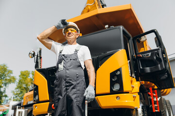 Man professional driver yellow big truck on building construction site. Concept industry worker