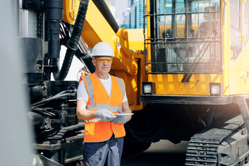 Portrait operator use mobile tablet for control drilling rig for exploration with sun light. Modern...