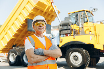 Mining industry truck driver in hard hat on background cabin of his lorry. Concept industrial...