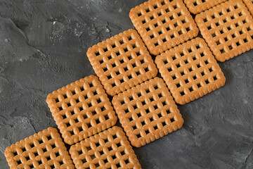 Sweet square cookies with holes on a grey background.