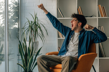 young man sitting on the sofa at home excited celebrating with joy and enthusiasm