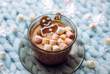 Gingerbread man soaking in a cup of hot chocolate with marshmallows, cozy winter setting in home.