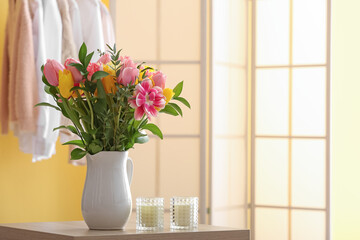 Vase with flowers and candles on table in room