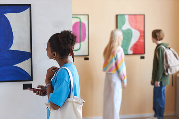 Colorful shot of diverse group of teenagers looking at art in modern art gallery or museum, copy space