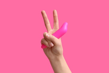 Woman with vacuum vibrator showing victory gesture on pink background