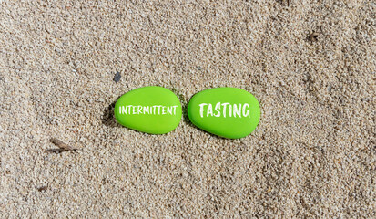 Intermittent fasting symbol. Concept words Intermittent fasting on beautiful green stone. Beautiful sand beach background. Healthy lifestyle intermittent fasting concept. Copy space.