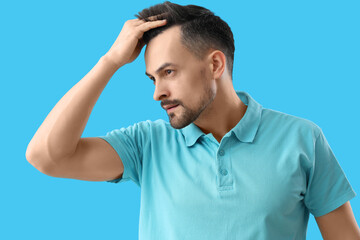 Handsome man with hair loss problem on blue background
