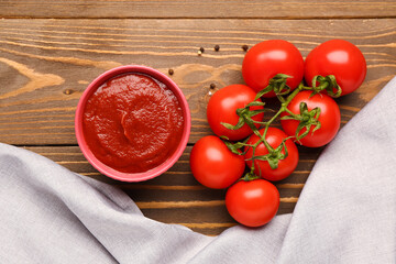 Bowl with tasty tomato paste and fresh vegetables on wooden background