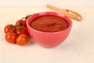 Bowl with tasty tomato paste and fresh vegetables on light background