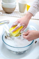 Woman washing spoon with sponge in sink, closeup