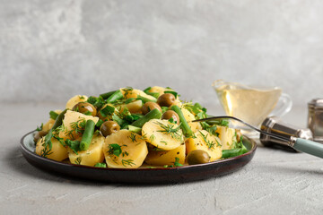 Plate of tasty Potato Salad with vegetables on grey background