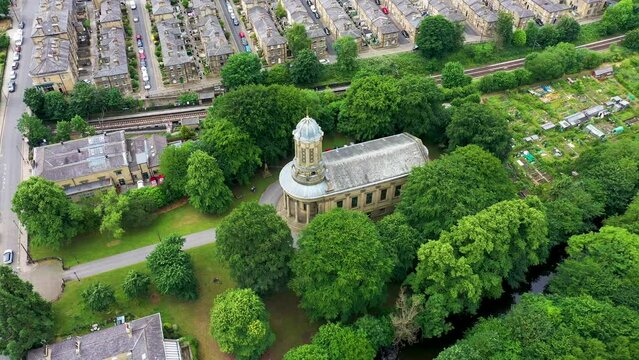 Aerial footage of the historic market town and civil parish of Shipley in the City of Bradford, showing the Saltaire United Reformed Church building in the summer time on a hot sunny day