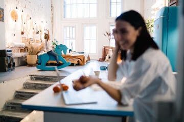 Child on rocking horse at home while mother working