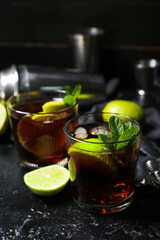 Glasses of tasty Cuba Libre cocktail on dark background