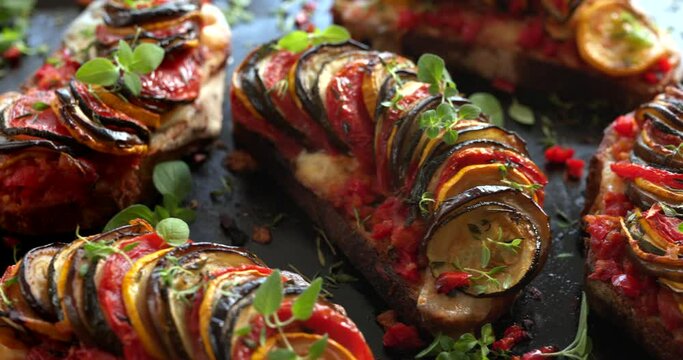 Grilled sourdough bread open faced sandwich with sliced vegetables and mozzarella cheese sprinkled with fresh herbs. Tian sandwich