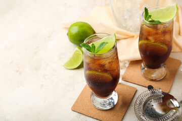 Glasses of cold Cuba Libre cocktail on light background