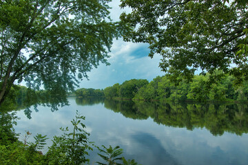 On a late Summer Afternoon, the peaceful Chippewa River reflects a moody sky and the surrounding forests near Lake Holcomb, WI.