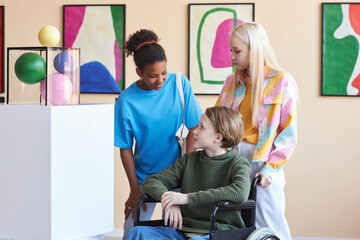 Obraz premium Inclusive group of friends with teen in wheelchair visiting art gallery together