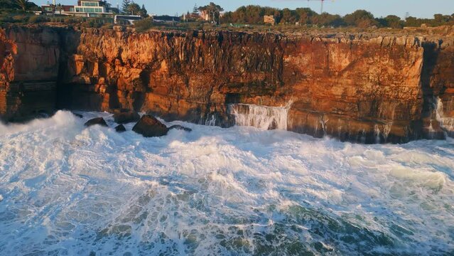 Foamy sea water hitting dangerous coastal rocks drone view. Stormy ocean waves 