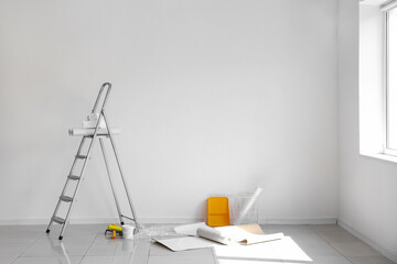 Wallpaper rolls with supplies and ladder in light room