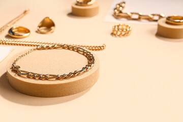 Decorative podiums with golden rings and bracelets on color background