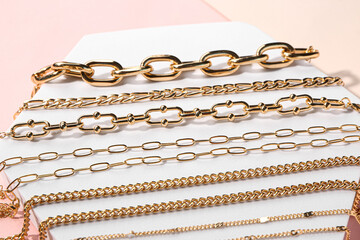 Decorative stand with golden bracelets and necklaces on color background