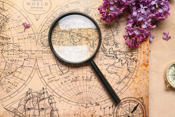 World map with compass, magnifier and lilac flowers on beige grunge background