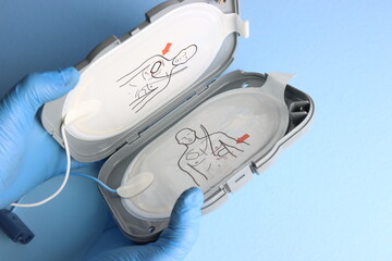 Defibrillator electrodes in the case beeing opened in a light blue background by a professional...