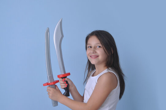 menina crian&ccedil;a  luta com espadas de brinquedo em fundo azul, luta divertida 