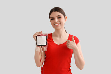 Female donor with blood pack for transfusion on light background